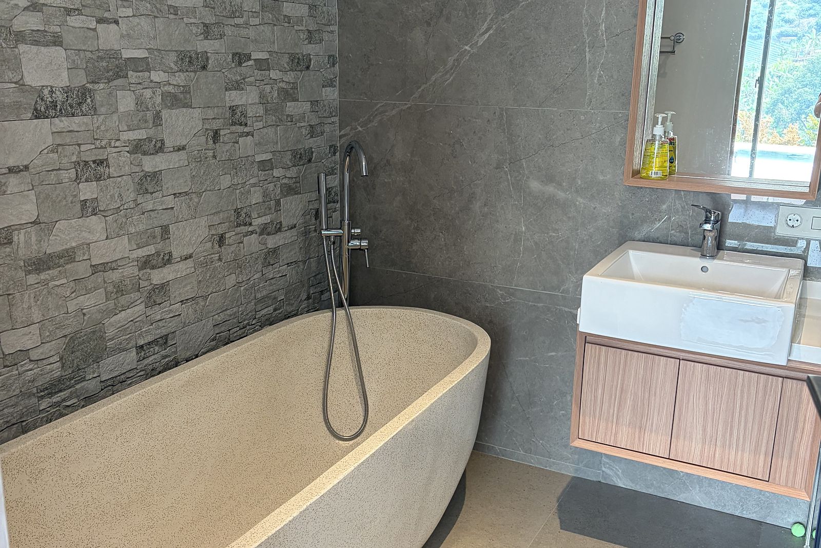 A freestanding stone bath in a stone-tiled bathroom