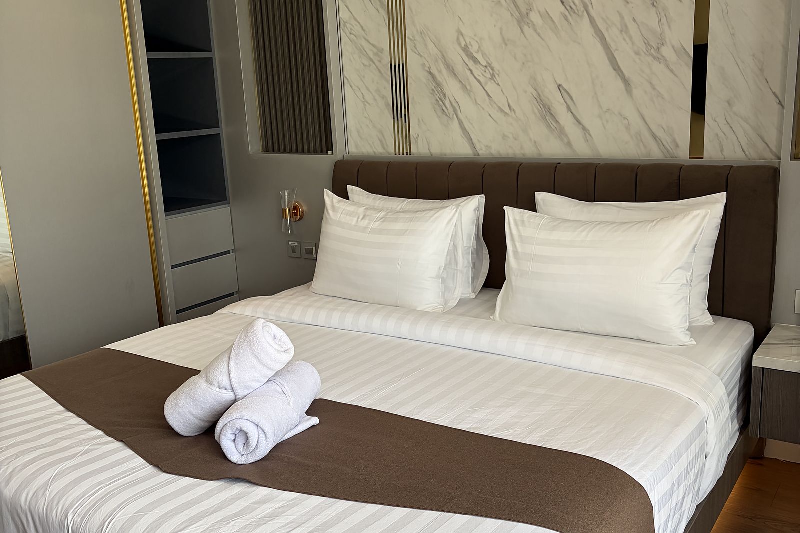A bedroom with a marble headboard wall and brass detailing