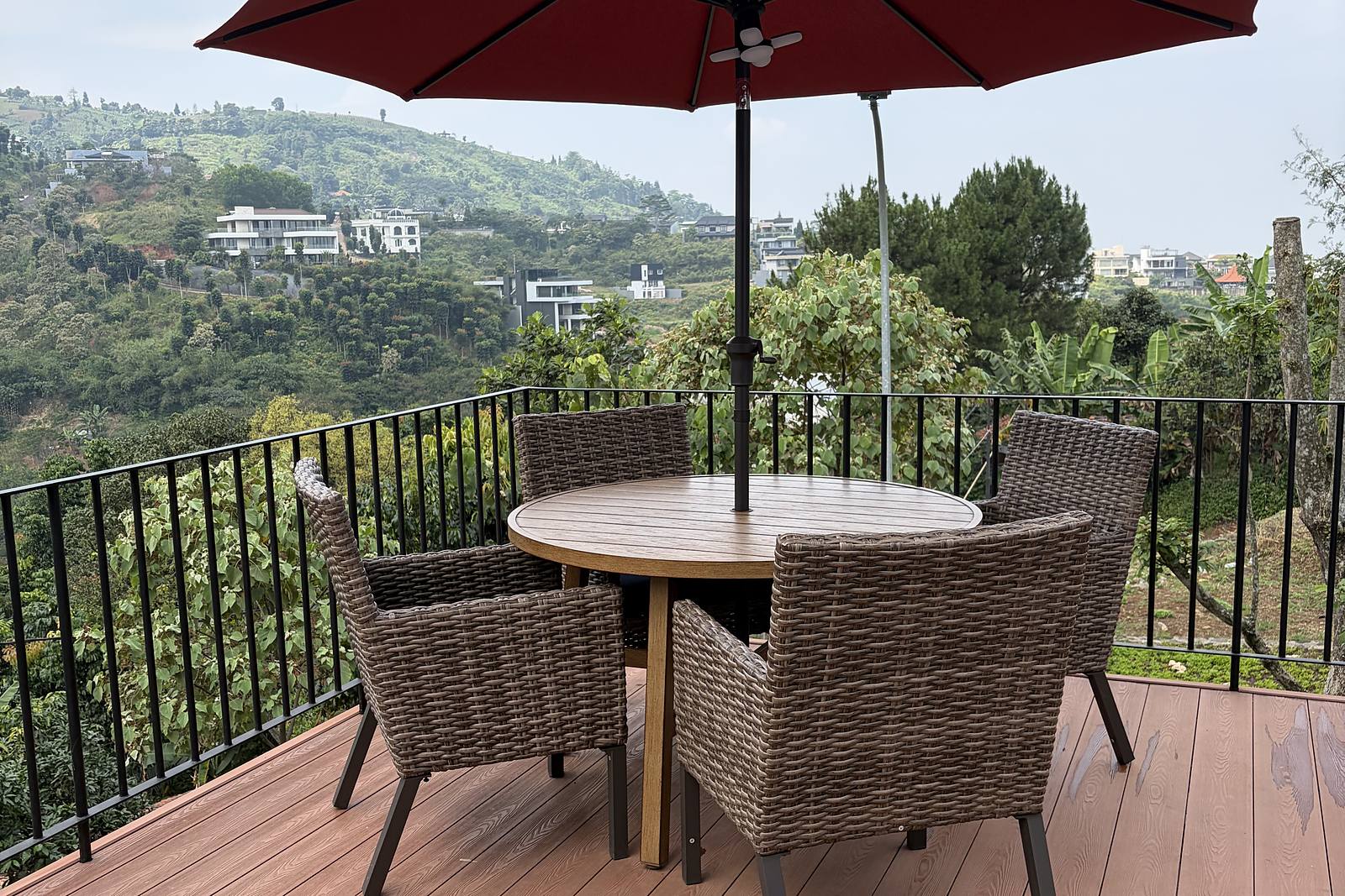 A dining table under a red parasol on the terrace, with the hills beyond