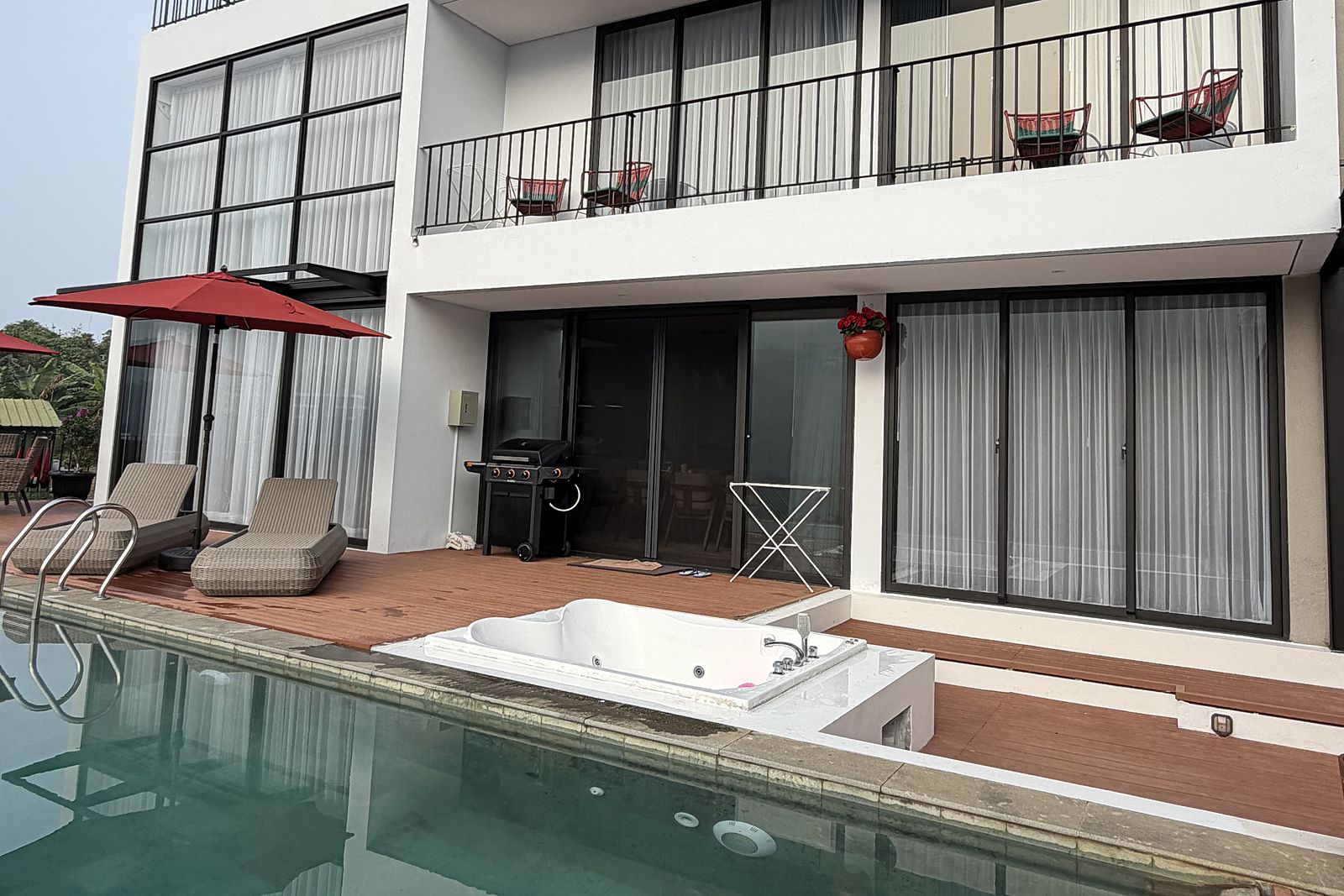 The villa's glass frontage reflected in the length of the pool